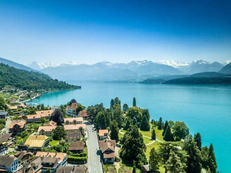 Luftaufnahme einer Schweizer Seegemeinde am türkisblauen See mit Alpenpanorama – Seelage als wertsteigernder Faktor bei der hedonischen Immobilienbewertung