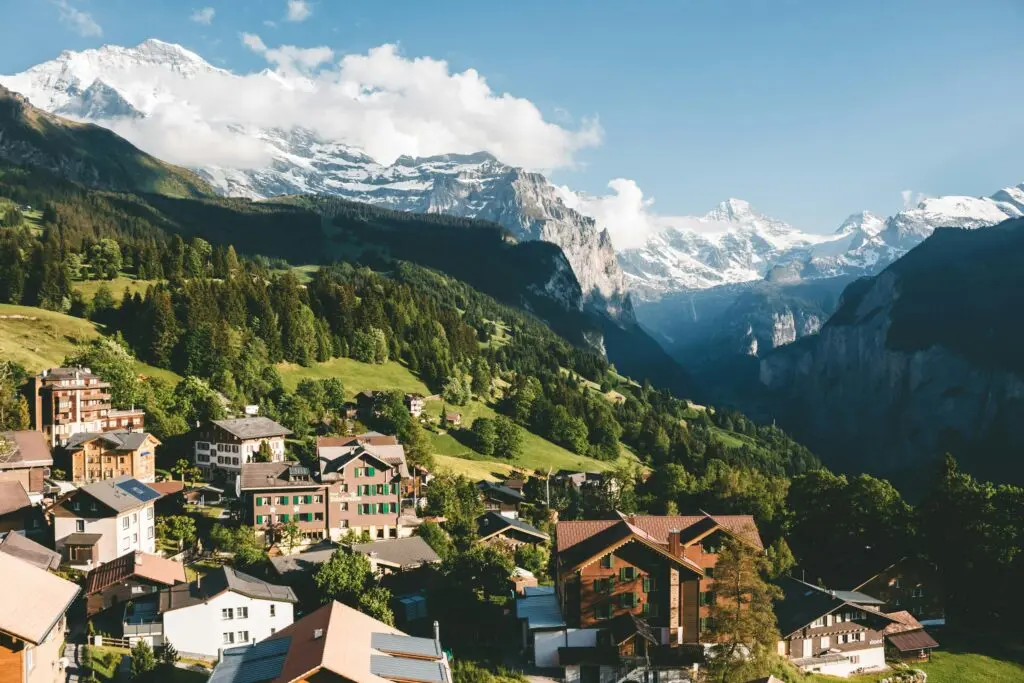 Kleines Schweizer Bergdorf auf grüner Blumenwiese vor imposanter Felswand im Lauterbrunnental