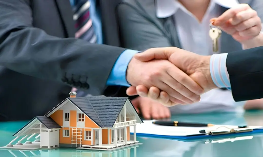 Handschlag zwischen Immobilienmakler und Kunde mit Hausmodell und Schlüsselübergabe